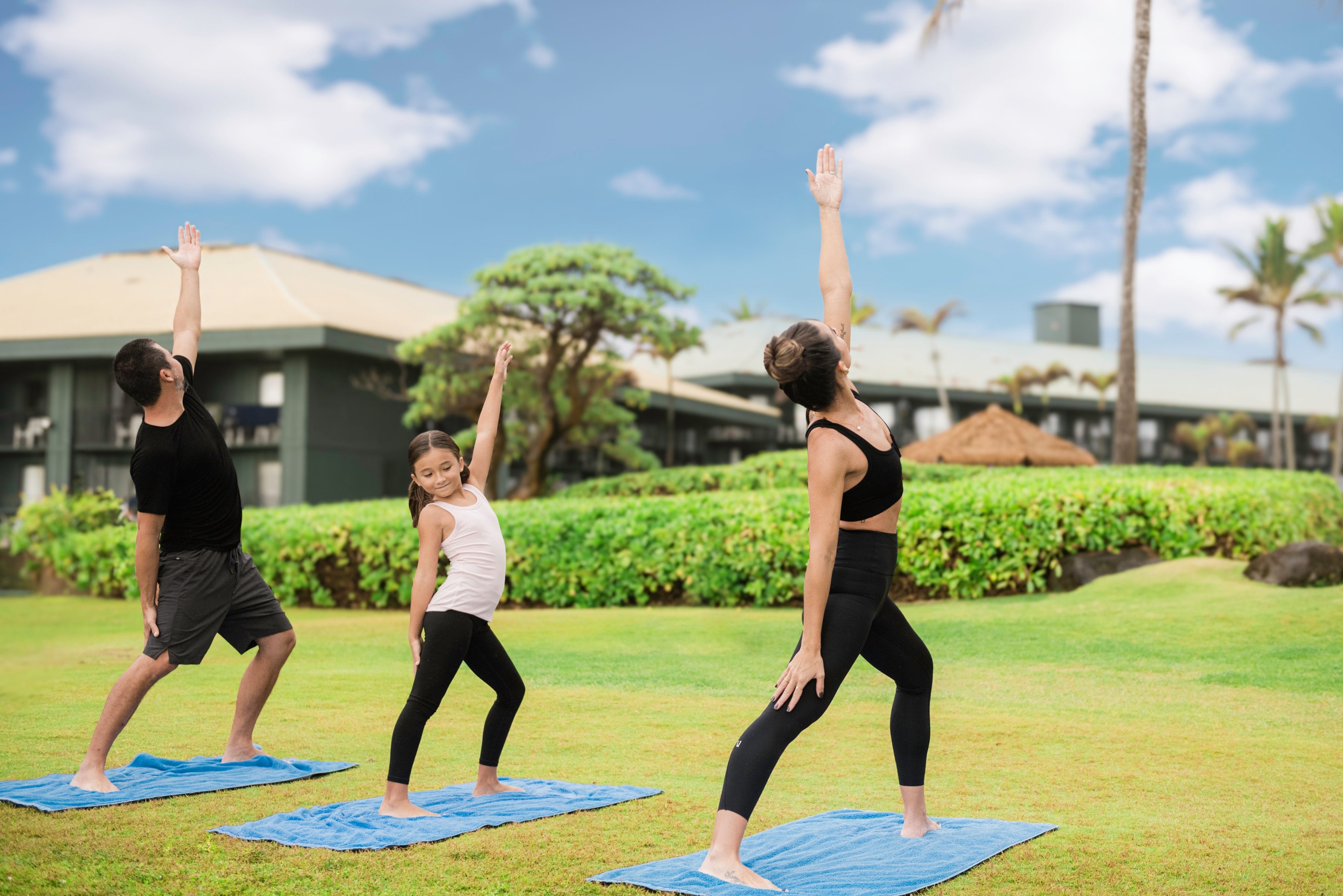 Guests doing yoga on the lawn in front of the beach at OUTRIGGER Kauai Beach Resort & Spa