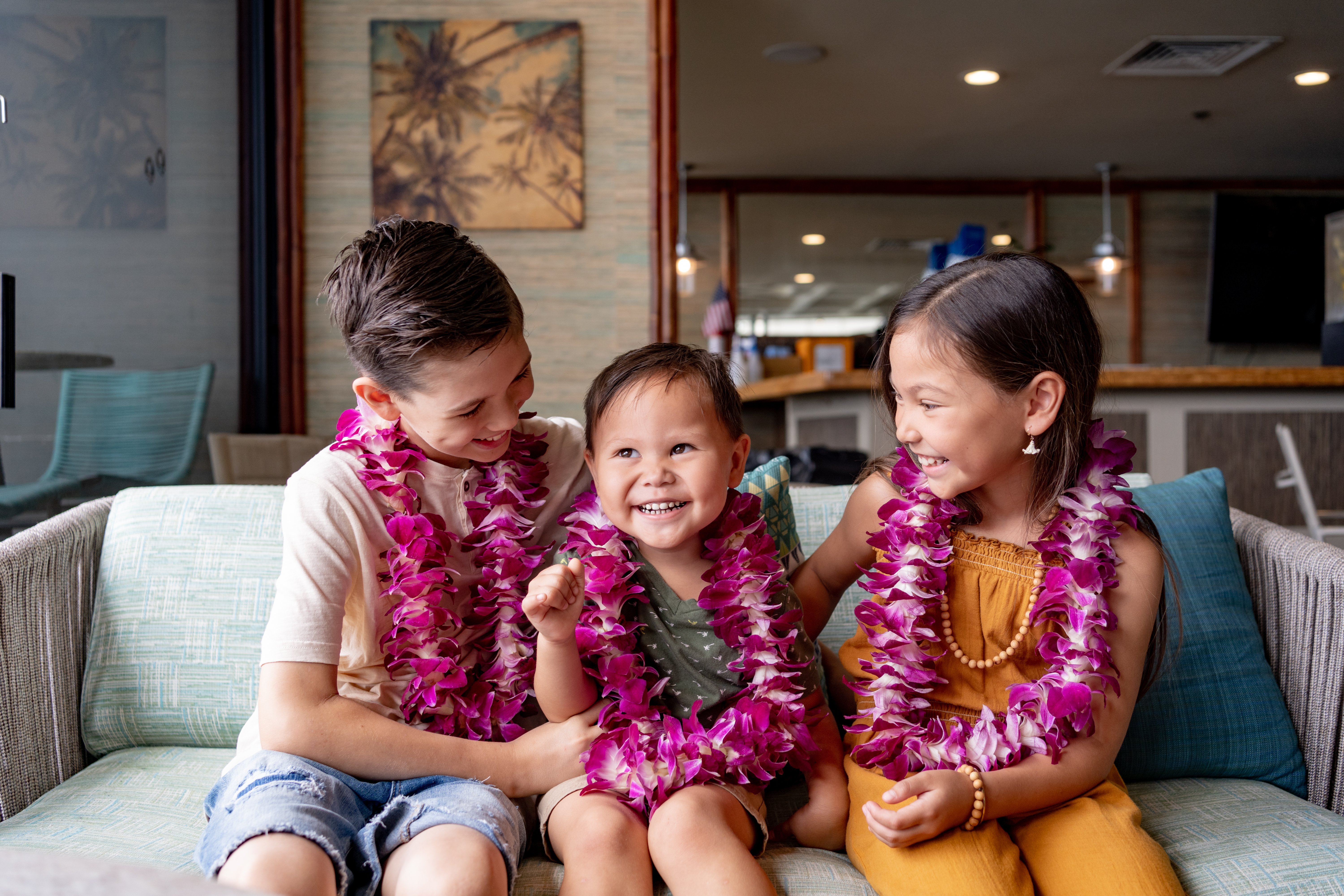 Three young kids wearing lei and smiling