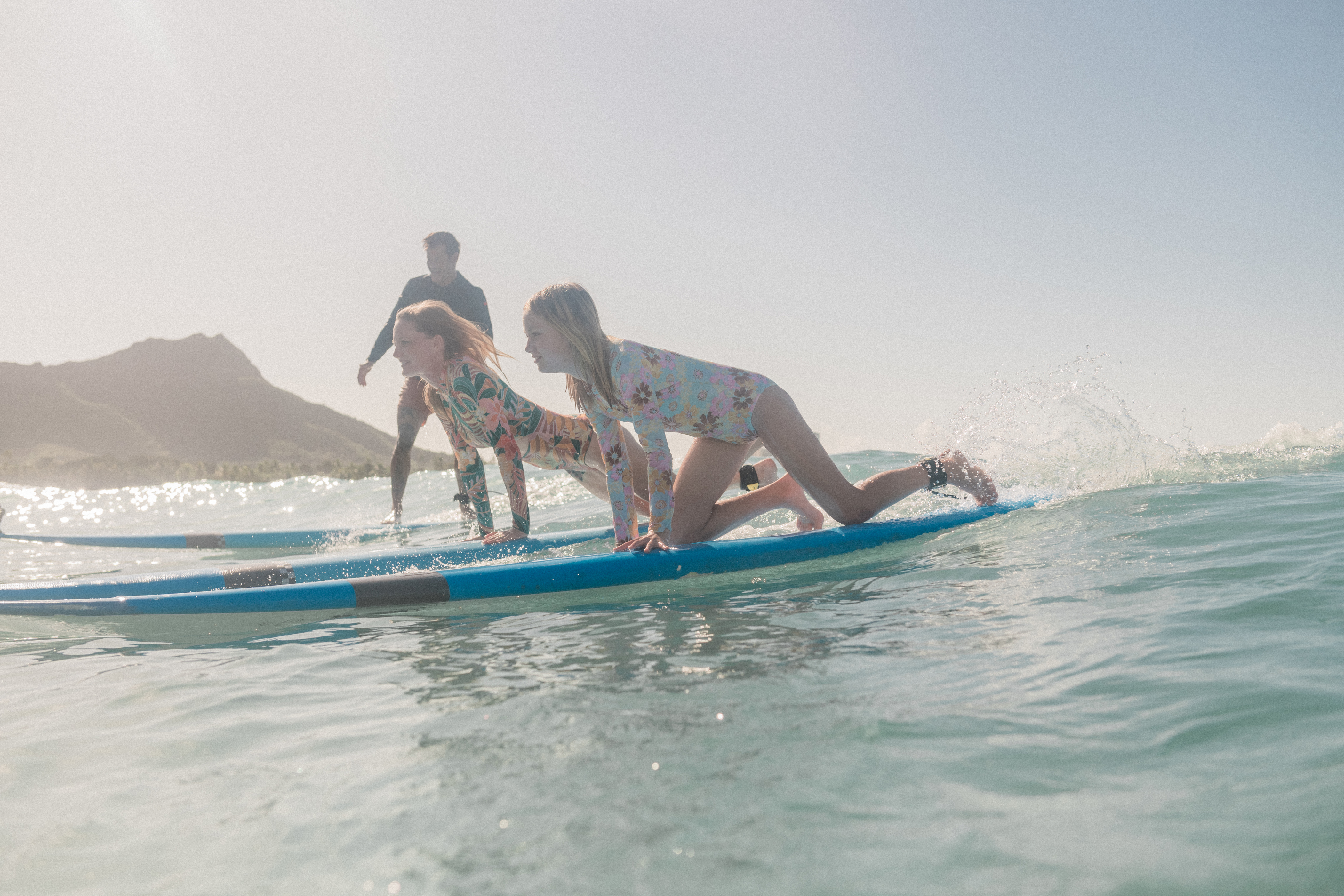 Two girls learning to surf on a wave in Waikiki